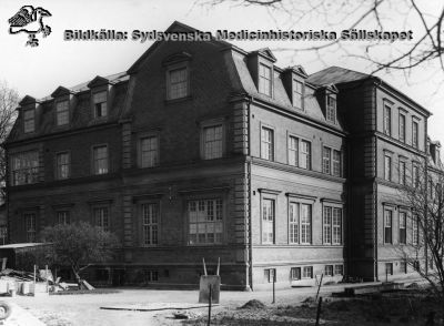 Gamla barnkliniken på södra lasarettsområdet. Västerfasad.
Bild i Regionarkivet utan indexeringsstödjande information. 
Foto rimligen under 1900-talets första halva. Skottkärran och byggnadsmaterialet antyder att huset har just blivit färdigt.
Nyckelord: Barn;Barnklinik;Södra;Lasarettet;Lund