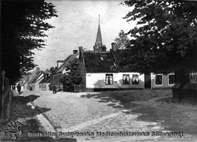 Norra Vallgatan i Lund år1912. 
Efter en målning. Vy västerut med Allhelgonakyrkan i bakgrunden. Gatan lades igen och husen på gatans norra (högra) sida revs för utvidningen av södra lasarettsområdet något år senare.
Nyckelord: Kapsel 01;Regionarkivet;Lund;Norra;Vallgatan;1912;Målning