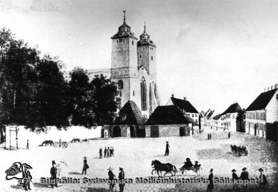 Lilla Torg och Stora Kyrkogatan i Lund omkring 1830. 
Lundagård med sin mur och domkyrkan i bildens vänstra halva. Universitetsapoteket Svanens byggnad är nr 2 från höger. Efter akvarell av G. W. Palm
Nyckelord: Kapsel 01;Regionarkivet;Lund;Stor;Kyrkogatan;Domkyrka;Apotek;Svanen;Universitetsapotek