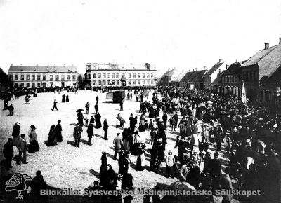 Mårtenstorget i Lund från väster.
Standar med texten "Åtta timmars arbetsdag" i bildens högra del antyder att den är tagen från en första maj-demonstration. Klädedräkterna antyder decennierna nära sekelskiftet 1900. Reprofoto av okänd proveniens
Nyckelord: Kapsel 01;Regionarkivet;Lund;Mårtenstorget;Demonstration;Första;Maj;1900