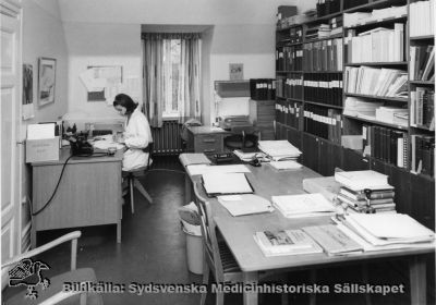 Ett sekreterarrum 1968, rimligen anestesiologen "Nilla" Nilssons sekreterare
Påskrift: "LL:s-område norr: interör." Fotograf okänd. Foto monterat på kartong. Från samma negativ som SMHS12337.
Nyckelord: Kapsel 02;Regionarkivet;Lasarettet;Lund;Sekreterarrum;Kirurgi;Anestesi;Narkos