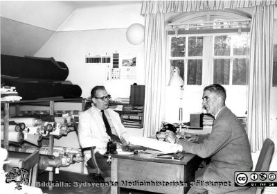 Maskinmästare Gösta Svensson och tapetserarmästare Malm 1960
Omonterat och omärkt foto i  mapp från lasarettsdirektörens arkiv märkt "Paradisgatan + annat gammalt. Fotoarkiv". Bilden visar uppenbarligen tapetserarverkstaden vid Lasarettet i Lund. På bild 101104-061 är personerna namngivna: "Mask.mäst. Gösta Svensson" (till höger i bild) och "Tapetserarmäst. Erik (?) Malm" (till vänster i bild). Bildens negativ har hittats 2015, och den togs 1960. Se bilderna SMHS14076ö och SMHS14077.
Nyckelord: Lasarettet;Lund;Universitet;Universitetssjukhus;USiL;MTA;Verkstad;Administration