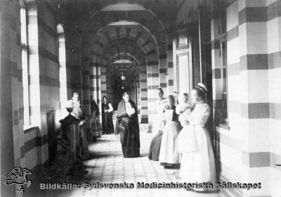 Korridor i kirurgiska kliniken i Lund år 1901
Påskrift: "Interiör från lasarettet i Lund 1901. Två Sophiasystrar med Ebba i bakgrunden. Foto från Ebba Lagströms efterlämnade handlingar". - Foto monterat på kartong.
Nyckelord: Kapsel 02;Regionarkivet;Lasarettet;Lund;Kirurgi;Kirurgisk;Klinik;Ebba;Lagström