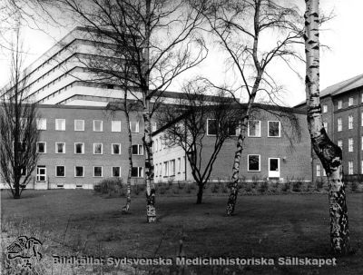 Barnpsykiatriska kliniken, från 1986 Ögonkliniken B
Påskrift: "Barnpsykiatrisk klinik. Foto i lasarettsarkivet." Fotografi monterat på tjock kartong. Foto från sydost. Årtal saknas, men kliniken invigdes i oktober 1965. Det bakomliggande centralblocket vid Lasarettet i Lund stod färdigt 1968. Bilden bör alltså vara tagen tidigast på sent 1960-tal eller senare; senast 1985 då huset började göras om till ögonmottagning, sedan barnpsykiatrin hade flyttats ned till St Lars-området.
Nyckelord: Kapsel 03;Regionarkivet;Lasarettet;Lund;Barnpsykiatrisk;Klinik;Ögon;