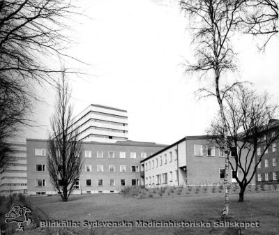 Barnpsykiatriska kliniken, från 1986 Ögonkliniken B
Påskrift: "Barnpsykiatrisk klinik. Foto i lasarettsarkivet." Fotografi monterat på tjock kartong. Foto från sydost. Årtal saknas, men kliniken invigdes i oktober 1965. Det bakomliggande centralblocket vid Lasarettet i Lund stod färdigt 1968. Bilden bör alltså vara tagen tidigast på sent 1960-tal eller senare; senast 1985 då huset började göras om till ögonmottagning, sedan barnpsykiatrin hade flyttats ned till St Lars-området.
Nyckelord: Kapsel 03;Regionarkivet;Lasarettet;Lund;Barnpsykiatrisk;Klinik;Ögon;