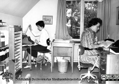 Två kontorister på administrationen på Lasarettet i Lund 1960
Omonterat foto märkt "Ulla Larsson" (till vänster i bild) och "Barbro Andersson" (till höger i bild), i mapp från sjukhusdirektörens kontor med påskrift "Fotoarkiv. Paradisgatan + annat gammalt". Foto troligast från sjukhuskontoret vid Valvet på södra lasarettsområdet. Skrivmaskinen är nog av mekanisk typ och telefonerna av s.k. petmojtyp, vanliga på 1950-talet. Negativet har år 2015 hittats i sjukhusfotografernas samling. Se bild SMhS14078.  Fotot är taget 1960, rimligen inför avflytten till norra lasarettsområdet lite senare. 
Nyckelord: Lasarettet;Lund;Universitet;Universitetssjukhus;USiL;Administration;Kontor;Kontorist