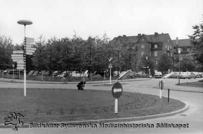 Rodelll framför AB-blocket på norra lasarettsområdet i Lund när det var nybyggt.
Omärkt bild. Originalfoto. Monterat.
Vägvisarens pilar åt vänster (norrut) pekar på de kliniker som fanns i det nya AB-blocket, och de som pekar åt andra hållet till de kliniker som ännu fanns och delvis finns söder om vägvisaren. Dåvarande ortopediska kliniken i bakgrunden. Foto på 1960-talet, tidigast 1959.
Nyckelord: Kapsel 18;Lund;Lasarett;Område;Norra