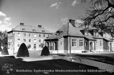 Epidemisjukhuset från år 1927: observationspaviljongen och administrationbyggnaden. 
Administrationbyggnaden i fonden kvarstår som lasarettets personalavdelning. Observationspaviljonen revs i början på 1960-talet för att ersättas med en ny infektionsklinik. Foto. Monterat
Nyckelord: Kapsel 18;Lund;Lasarett;Norra;Området;Infektion;Infektionsklinik