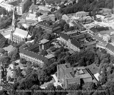 Flygfoto över norra lasarettsområdet i Lund, från sydost. 
Omärkt bild. Originalfoto. Monterat. Man ser dåvarande kvinnokliniken, medicinhska kliniken, sköterskehemmet, delar av öronkliniken och reumatologiska kliniken. Allhelgonakyrken ses uppe tilll vänster i bilden. Infektionskliniken i bildens övre högra kvadrant är under byggnad, dvs bilden bör vara tagen i mitten av 1960-talet.
Nyckelord: Kapsel 18;Lund;Lasarett;Norra;Området;Flygfoto;1960-talet.