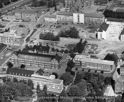 Flygfoto över norra lasarettsområdet i Lund, från söder
Nedifrån ses reumatoliogiska kliniken, i nästa rad öronkliniken längst till vänster, bredvid denna ortopediska kliniken och längre till höger ögonkliniken. Därovan länst till vänster radiologiska kliniken (= tidigare Jubileumskliniken) och till höger därom den plan som skall hysa det stora centralblocket. Därovan från vänster administrationsbyggnadens första etapp, AB-blocket och D-blocket. Längst upp dåvarande folkskoleseminariet. Foto i början av 1960-talet.
Nyckelord: Kapsel 18;Lasarett;Lasarett;Norra;Området;Flygfoto