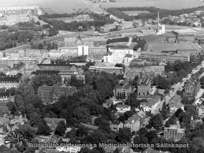 Flygfoto över nordöstra Lund (institutionsstaden) och norra lasarettsområdet i Lund, från sydost. 
Sölvegatan löper snett över bildens nedre högra del, genom institutionsstaden. Till vänster i bilden ses det trädomgärdade universitetsbiblioteket. Därovan ses i bildens mitt det ljusa nybyggda laboratorieblocket och till vänster om det AB-blocket, också nybyggt, med en mycket ljus central del där det blivande centralblocket skall ansluta. Foto i början av 1960-talet.
Nyckelord: Kapsel 18;Lasarett;Lund;Norra;Området;Flygfoto