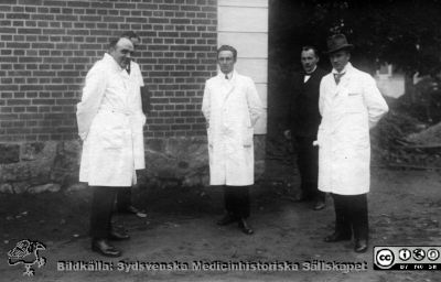 Läkare på St Lars sjukhus i Lund på 1920-talet
Från kapsel 20 med bilder från St Lars.  Professor V. Wigert, Doktor Bagger Jörgenssen, Kand Hugo Fröderberg, Doktor C. Loberg Uppsyningsman Ivar (?) Plomgren. Läkarna är klädda i vita rockar medan uppsyningsmannen har mörka kläder. Originalfoto under Wigerts tid i Lund, 1923 - 1929. Monterat
Nyckelord: Kapsel 20;St Lars;Lund;Personal;Läkare