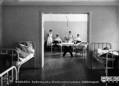 Vårdavdelning på "Asylen" i Lund (senare St Lars västra sjukhus)
Kapsel 22 med bilder från St Lars i Lund. Påskrifter: "Tillhör S:t Lars sjukhusmuseum, Lund, sovsalar, "asylen" 1929". "Asylen" lades formellt sett ned 1910 och blev Lunds Hospitals västra sjukhus, men namnet "Asylen" levde länge kvar. Originalfoto. Monterat
Nyckelord: Kapsel 22;St Lars;Lund;Patienter;Skötare;Interiör