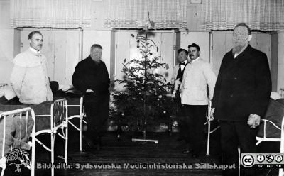 Personal och patienter på sjuksalen på St Lars, julen 1916
Kapsel 22 med bilder från St Lars i Lund. Vykort avstämplat i mars 1917 och med påskrifter: "Tillhör S:t Lars sjukhusmuseum, Lund"; "Personal och patienter på sjuksalen julen 1916"; Adressat: "Herr Viktor Svensson, Hospitalet, Lund". Korrespondens: "Uppsala den 20.3. Hej på dig din gamla broder! Torsdag kväll kl. 9.8, kommer jag till Lund med en patient. Hoppas att kanske får träffa dig då,  reser redan påföljande dag med första tåg åter mot norden. I hast P.A. Söderman". Originalfoto. Ej monterat.
Nyckelord: Kapsel 22;St Lars;Lund;Patienter;Skötare;vårdsal