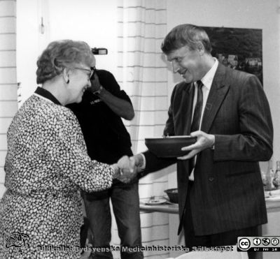 Direktionsordförande Mary Nilsson avtackar Bernt Petersson
Kapsel 23 med bilder från Eslöv-Orups-Hörbys sjukvårdsdistrikt. Påskrift på kuvertet det låg i: "Direktionen 1986-1988. Ordf. Mary Nilsson. Direktionen hela. Mary Nilsson. besök av prinsessan Christina aug-85. Studieresa till Bohuslän Nov.88. Avslut 1987 Kärråkra. 2784-2789 Dir. avtackning av Bernt Peterson". Ingen påskrift på bilden. Bernt Petersson avtackas av Mary Nilsson. Originalfoto. Omonterat.
Nyckelord: Kapsel 23;Orup;Eslöv;Hörby;Ordförande;Sjukhusdirektör;Avtackning;Direktion