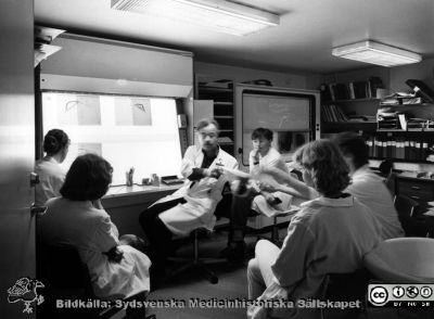 Onkologiska kliniken i Lund på 1980-talet. Dosplanering på högvoltsavdelningen
Foto Ola Terje låda A bild 13/11. Från vänster Lisa Kjellén (hårknut i nacken), 2. Gudrun Svahn-Tapper, 3. Överläkare Sten Graffman (vid ljusskåp med röntgenbilder), 4. Andrej Tomaszewicz, 5. Maria Albertsson, 6. Inger Erlandsson
Nyckelord: Terje;1980-talet;Onkologi;Klinik;Interiör;Konferens