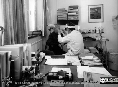 Onkologiska kliniken i Lund. Läkare (Torsten Andersson?) undersöker en patient i munnen.
Foto Ola Terje låda A bild 42/5. Slutet på 1980-talet. 
Nyckelord: Terje;Onkologisk;Onkologi;Klinik;Lund;Interiör;1980-talet;Undersökning;Undersökningsrum