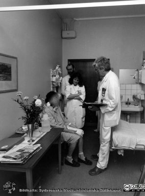 Onkologiska kliniken i Lund. Läkarrond på vårdrum.
Foto Ola Terje låda A bild 44/12. Slutet på 1980-talet. 
Nyckelord: Terje;Onkologisk;Onkologi;Klinik;Lund;Interiör;1980-talet;Rond;Patient