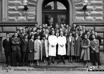 Kursfoto, medicinarnas nybörjarkurs höstterminen 1959 i Lund
Kapsel 27. Fotoarkiv. Anatomiska instutionen. Kursfotografier från 1950- och 1960-talen. Höstterminen 1959. Originalfoto på anatomiska institutionens trappa. Prosektor Folke Löfgren och professor Carl-Herman Hjortsjö i första radens mitt. Ingmar Rosén i slips och mörk kavaj men utan glasögon framför portens högra del. Kanske Göran Göransson bakom hans högra axel, och Per Befrage bakom Göranssons högra axel. Björn Jonsson mellan Löfgren och Hjortsjö. Kanske Mattias Hallgren bakom Belfrages högra axel. Troligen Kennerth Wilke bakom Löfgrens högra axel. 
Nyckelord: Kapsel 27;Kursfoto;Anatomi;Amphioxer