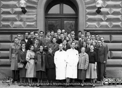 Kursfoto, medicinarnas nybörjarkurs höstterminen 1955 i Lund
Kapsel 27. Fotoarkiv. Anatomiska instutionen. Kursfotografier från 1950- och 1960-talen. Höstterminen 1955. Originalfoto på anatomiska institutionens trappa. Professor Carl-Herman Hjortsjö och prosektor Folke Löfgren i vita laboratorierockar i mitten på första raden. Av kursdeltagarna finns på bilden i främre raden Ann Malmquist (då Lundgren), Agneta Kullenberg (då Welin), Marlene Lindberg (då Andreska), Margareta Post, Kerstin Erlandsson (då Schelin), Gunilla Ahlbeck (då Norgren). I andra raden ses Bo Eklöf, Torgil Möller, Lars Malm, Allan Eddeland, Anita Bråkenhielm (då Ohlander), Ulla Larsson (då Nyberg), Bengt Bengtsson, Ingrid Ganrot (då Ottosson), Per Ahlbeck.Bakre raden från vä: Göran Lindstedt, Lars Kullenberg, Lars-Åke Bliding, Jörgen Malmquist, Emil Carlin, Karl-Henning (Kalle) Fredlund, Ulf Malm, Björn Nylander, Lennart (Lelle) Malmberg, Ulf Svenmo, Ulf Norrsell, delvis dold Bengt Axmacher, Alf Elman, Carl-Olof Erlandsson, Thomas Olivecrona, Göran Nilsson, Olof Bynke, Stig Persson, Tom Saldéen, Bengt Bengtsson. Tord Jerndahl, Bengt Sundström, Leif Rosenhall.
Följande saknas på fotot av HT55 utanför anatomen: Per-Olof Ganrot (då Månsson), Jan-Erik Gierup, Sven Lundberg, Staffan Nordqvist, Lars Olsson, Gunnar Persson, Hans Selander, Kerstin Strömland (då Richardsson) och Hans Werner.  Namnsättning av Lars Malm 2018.
Nyckelord: Kapsel 27;Kursfoto;Anatomi;Amphioxer