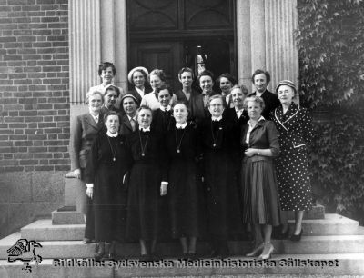 Återsamling av sjuksköterskekurs på SSSH i Lund 1929-1932, vid utdelning av silverkedja
Fotot ligger i ett häfte med påskrift "Utbildning sjuksköterskor, deltagare i årskurs 1929 - 1932 vid erhållen silverkedja. Överlämnad 15 maj 1991. 
Fotograf: Jensen Foto, Lund, på entrétrappan till dåvarande SSSH.
Nyckelord: SSSH;Silverkedja;Sjuksköterska;1991;Jensen;Foto;Gruppfoto Utbildning;SSSH