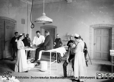 Kirurgens poliklinik i Lund år 1905
Påskrift på annan kopia (SMHS2520) av samma negativ: "Lunds kir. poliklinik år 1905. Tillhör prof. G. Petrén, Lund.". 
Gustaf Petrén var ännu inte professor när bilden togs. Kirurgiska kliniken var nyrenoverad. Foto monterat på tjock papp. Rahmns foto, Lund.
Nyckelord: Kapsel 29;Lasarettet;Lund;Kirurgi;Poliklinik;Operationssal