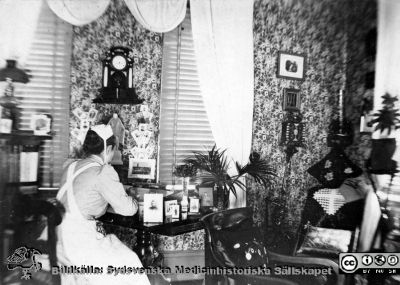 Okänd sköterska i sitt hem, rimligen i slutet på 1800-talet
Kapsel 30. Omärkt bild. Interiör som i slutet på 1800-talet. Notera fotogenlampan i bildens vänstra kant. Originalfoto. Monterat
Nyckelord: Kapsel 30;Personal;Sköterska