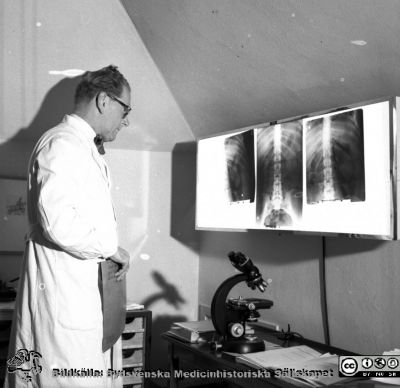 Prof Helge B Wulff granskar röntgenbilder. 
Pärm äldre neg. 1951-1958 MAS, från fotograf Björn Henrikssons samling. Kirurgiska kliniken, Malmö Allmänna Sjukhus. Negativ
Nyckelord: MAS;Malmö;Kirurgi