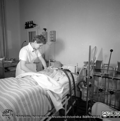 Malmö Allmänna Sjukhus. Respiratorpatient i Lundiarespirator. 
Pärm äldre neg. 1951-1958 MAS, från fotograf Björn Henrikssons samling. Påskrift: "Doc von Rosen, Ortop. + Epid. 26/4-56". Infektionskliniken. Negativ
Nyckelord: UMAS;MAS;Malmö_;Allmänna;Allmänna;Ortopedi;Respirator;Infektion;Andningsvård