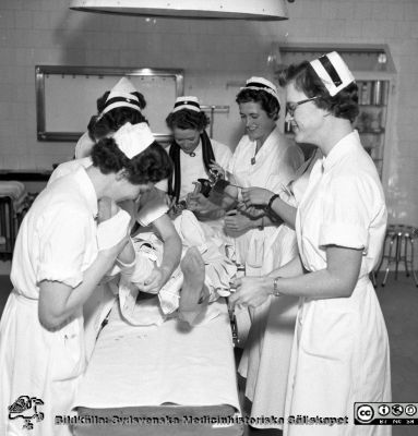 Systrarna hittar på bus på kirurgiska kliniken i Malmö år 1957
Pärm äldre neg. 1951-1958 MAS, från fotograf Björn Henrikssons samling. Kir op, 18/4-57. Troligen sofiasystern Elisabeth Borstam som nr 2 från höger. Från negativ
Nyckelord: UMAS;MAS;Malmö;Allmänna;Sjukhus;Kirurgi;Hippa;Fest;Sköterskor