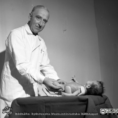 Doc Sophus von Rosen med sin skena för nyfödda med ofullständigt utvecklade höftleder
Pärm neg. 1962-1966. Från fotograf Björn Henrikssons samling. Påskrift: "Doc Sophus von Rosen. 20/3-65". 
Här med ett barn i den skena han konstruerat. Från negativ
Nyckelord: UMAS;MAS;Malmö_;Allmänna;Sjukhus;Ortopedi;von Rosen-skena;baby;Nyfödd;Spädbarn