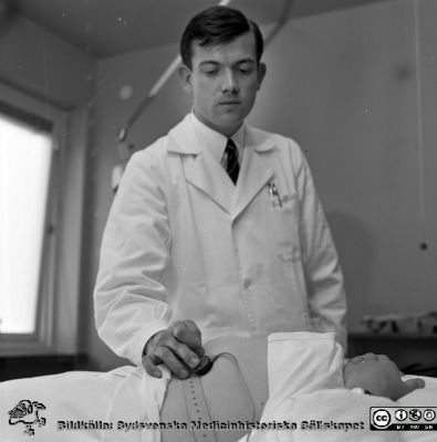 Dr Percy Liedholm lägger apparat på en gravid kvinnas buk 1966
Pärm neg. MAS 1962-1966. Från fotograf Björn Henrikssons samling. Påskrift: "Arbetet, Rumsby, reportage, förlossning, 26/10-66". Från negativ
Nyckelord: UMAS;MAS;Malmö_;Allmänna;Sjukhus;Kvinnoklinik;Graviditet