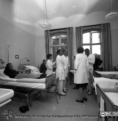 Rond på gamla öronkliniken i Malmö.
Pärm negativ MAS 1972-1977. Från fotograf Björn Henrikssons samling.	Omärkt bild, öronkliniken Malmö Allmänna Sjukhus. Rond. Från vänster, stående: NN1, Lars Andréasson, Ingvar Frenander, NN2s rygg, NN3 skymd, Jan-Åke Wihl. Från negativ
Nyckelord: UMAS;MAS;Malmö;Allmänna;Sjukhus;Öronklinik;ÖNH;Oto-rhino-laryngologi;Vårdsal;Rond