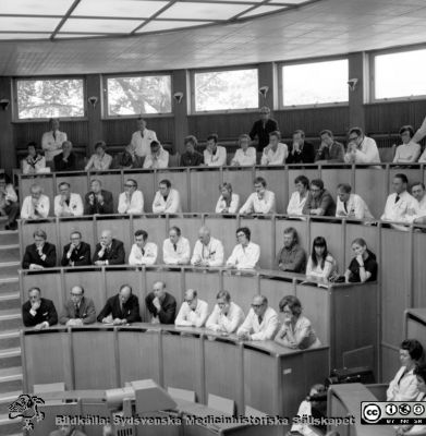 Professor Jan Waldenström vid sin avskedsföreläsning i aulan på Malmö Allmänna Sjukhus 9/6 1972
Pärm negativ MAS 1972-1977. Från fotograf Björn Henrikssons samling. Prof. Waldenström avtackas 9/6-72. På första raden fr vä: privatpraktikern i Malmö, Stellan Forsberg,  utbildad  på med klin, Jonte Dymling, Jan Hällén, överläkare  i Västerås, disputerat  på med klin, Stig  Berglund, disputeras samma  år  på med klin på en malmöfamilj med muterat hemoglobin, Sten Eriksson / alfa1-antitrypsin, NN3 och NN4. Andra raden nedifrån, från vänster: Privatpraktiker Axel Larsson, möjligen överläkare  Fredrik (?) Nyström, Kalle Gydell, patologen Claes Lindström som 1976 beskrev collagen colitis, Bengt  W Johansson, möjligen Ingemar  Turesson, Görel Östberg. På tredje raden nedifrån, från vänster: kanske Georg Theander, Lars Andrén, samt lungläkaren Nils Kalén som nr 2 från höger i raden. Stående, längst upp till vänster Rolf Backman. Sittande framför honom Anders Wenckert (?). Stående kirurgen Göran Ekelund, och framför honom med huvudet i händerna Bertil Nosslin. Sven Genell nr 4 höger ut i bild på översta raden. Lennart Leandoer nr 5 och Göran Balldin nr 6. Från negativ
Nyckelord: UMAS;MAS;Malmö;Allmänna;Sjukhus;Medicin;Aula;Avtackning