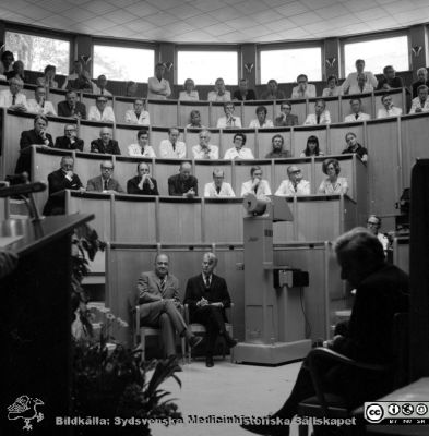 Professor Jan Waldenströms avskedsföreläsning i aulan på Malmö Allmänna Sjukhus 9/6 1972
Pärm negativ MAS 1972-1977. Från fotograf Björn Henrikssons samling. Prof. Waldenström. 9/6-72. På parkett från vä NN, Sven-Erik Björkman, Bernt Hökfelt. Närmast kameran Nils Söderström i silhuett. På gradängens andra rad, nr 5 Stig Berglund, 6 Sten Eriksson. På tredje raden nr 3 från vä, Carl Gydell, nr 4 patologen dr Lindström, 5. Bengt W. Johansson, 6. Folke Linell, 7.Görel Östberg. På gradängens fjärde rad Georg Theander, Lars Andrén, Jan Gunnar "Pothas" Nordén. Halvor Möller längst till höger. Från neg.
Nyckelord: UMAS;MAS;Malmö;Allmänna;Sjukhus;Avtackning;Pensionering;Aula;Föreläsning