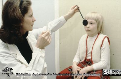 Synundersökning på ett barn, ögonkliniken i Lund 1979
En ortoptist undersöker ett barn på ögonkliniken i Lund år 1979
Nyckelord: Lasarettet;Lund;Universitet;Universitetssjukhus;Ögon;Ögonklinik;Ögonläkare;Undersökning;Skelning;Prisma;Förtäckning;Covertest