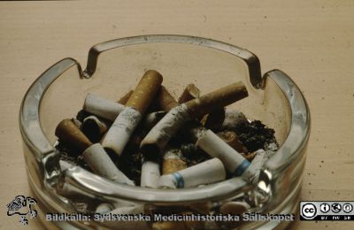 Cigarrettfimpar i en askkopp av glas
Ur låda med blandade diabilder från sjukhusfotograferna i Lund, 1970-, 1980- och 1990-talen. Askkopp fylld med cigarettstumpar.
Nyckelord: Lasarett;Lund;Universitet;Universitetssjukhus;Rökning;Askkopp;Cigarrett;Fimp