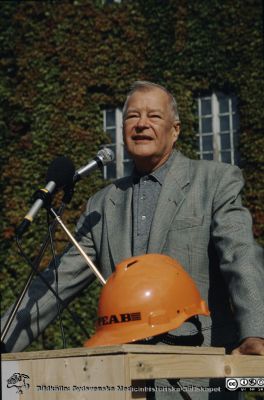 Kommunal- och landstingspolitikern och direktionsmedlemmen Torsten Engvall (1930-2005) i talarstolen vid någon bygghändelse
Lasarettet i Lund.  Foto rimligen på 1980-talet. Troligast gamla folkskoleseminariet i bakgrunden.
Nyckelord: Lund;Lasarett;Universitet;Universitetssjukhus;Landsting;Politiker;Kommunalråd;Landstingråd;Administration;Ordförande