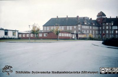 Folkskoleseminariet med norr därom liggande tillfälliga baracker
Ur låda med blandade diabilder från sjukhusfotograferna i Lund, 1970-, 1980- och 1990-talen. Bild utan beskrivning. Baracker för sjukhusets administration i slutet på 1970-talet när dåvarande administrationslokaler renoverades och byggdes om (de i gamla infektionskliniken och i administrationshuset vid huvudingången, färdigt 1960). 
Nyckelord: Lasarett;Lund;Universitetssjukhus;USiL;Administration;Folkskoleseminarium