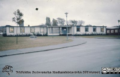 Baracker för tillfälliga administrationslokaler strax norr om gamla seminariet
Ur låda med blandade diabilder från sjukhusfotograferna i Lund, 1970-, 1980- och 1990-talen. Bild utan påskrift. Här inhystes sjukhusledningen i slutet på 1970-talet, Husen revs i början på 1980-talet. Nya patologiska institutionen anas i bakgrunden till vänster i bilden. Längre till höger i bakgrunden gamla vattentornet. 
Nyckelord: Lasarett;Lund;Universitetssjukhus;USiL;Administration;Barack