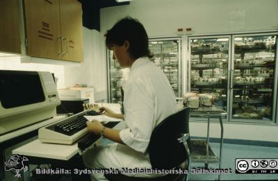 Interiör på blocentralen i Lund
Ur låda med blandade diabilder från sjukhusfotograferna i Lund, 1970-, 1980- och 1990-talen. Bild utan påskrift. Blodpåsar kontrolleras. Rimligen på blodcentralen.
Nyckelord: Lasarettet;Lund;Universitetssjukhuset;USiL;Blodcentralen;Laboratorium