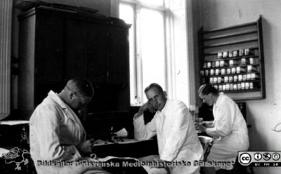 Fotoalbum tillägnat Professor Torsten Hellman från histologkursen 1929. 
Fotoalbum tillägnat Professor Torsten Hellman med tacksamhet och vördnad från histologkursen 1929. Albumtext "Hans Österlind. Cavallin. Marianne Lindsten". Kursdeltagare  i kurslaboratoriet vid en arbetsbänk. 
- Hans Österlinds fortsatta vägar är okända. 
Knut Cavallin (1908 - 1995) blev internmedicinare och så småningom uppskattad och välkänd provinsialläkare  i skånska Borrby från 1951. Dottern Ulla Cavallin Sjöberg är i september 2025 osäker på om identifieringen är rätt.
Marianne Lindstén-Thomasson (1909-1979) hade olika  Internmedicinska tjänster och blev sedan provinsialläkare i först Vilhelmina 1946 - 1955 och därefter i Lycksele. Hon var Sveriges första kvinnliga provinsialläkare och mycket uppskattad.
Nyckelord: Histologiska avdelningen;Anatomiska Institutionen;Medicinska fakulteten i Lund;Locus Medicus Lundensis;Universitet;Kurslaboration