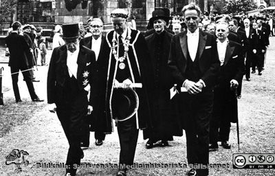 Extra promoveringen i samband med universitetets 300-årsjubileum 1968. 
Philip Sandblom (1903 - 2001), professor i kirurgi vid Lunds Universitet från 1950, Rector Magnificus där 1957 - 1968. Här tillsammans med på sin högra sida f. universitetskanslern, f. landshövdingen mm Arthur Thomson och på sin vänstra landshövding Gösta Netzén vid uttåget ur domkyrkan i Lund efter den extra promoveringen i samband med universitetets 300-årsjubileum 1968. Själv bär han lagerkrans, eftersom han just promoverats till filosofie hedersdoktor. I andra ledet ser man NN, prorektor Per Stjernquist och (i halskedja) landstingsrådet Torsten Andrée.
Nyckelord: Kapsel 01 Regionarkivet