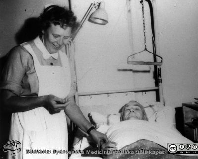 Syster Marta "pulsar" på urologiska kliniken i Lund i mitten på 1900-talet.
Avdelningsföreståndaren Marta Ängeby (1908-2003) arbetade länge på urologiska kliniken i Lund i gamla kirurgibyggnadent, ´Här tar hon pulsen (hjärtslagsfrekvensen på en patient.
Nyckelord: Urologisk;Kirurgisk;Lund;Avdelningssköterska;Klinik;Universitetssjukhuset;USiL;Lasarettet;Kapsel 11