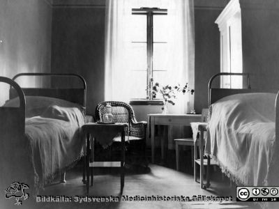 Rum för 2 patienter, s.k. halvenskilt rum, på ögonkliniken i Lund i mitten på 1920-talet.
Bilden finns publicerad i A. Flaum, Lasarettet i Lund 1768 - 1968 (Lund: Malmöhus läns landsting, 1968), p. 165, och anges där vara tagen omkring 1900, vilket inte förefaller trovärdigt eftersom den sitter i ett album producerat i mitten av 1920-talet för professor Gustaf Ahlström inför hans pensionering 1927.
Nyckelord: gon;Klinik;Lasarettet i Lund;Medicinska fakulteten;Halvenskilt;Sjukrum;Vårdrum