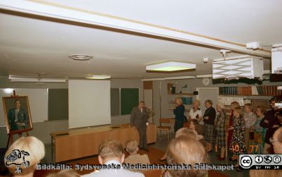 Urologiska kliniken i Lunds 20-årsjubileum 1977
Album Urologiska klinikens 20-årsjubileum 1977-10-01. Professor Gösta Jönssons porträtt framvisas. Gösta Jönsson själv vid katedern. På främre stolsraden i ljusbrun kostym med ryggen mot kameran: Professor Lennart Andersson, Stockholm. Övriga sittande är ej identifierade. Stående vid bortre väggen, från vänster: okänd (skymd), okänd, sjuksköterskan Anna-Brita Hammarberg (röntgen; i ljusa kläder), Sjuksköterskan Marianne Nilsson (mörk polotröja och glänsande halsband), nattsjuksköterskan Carin Lundblad (rutiga kläder), sjukvårdsföreståndaren Mary Mattsson ( röda kläder och avdelningsföreståndare Eva Ljunggren i stormönstrad klänning, okänd, okänd, dr Anders Ek längst till höger. Bildkälla: Bengt Uvelius.
