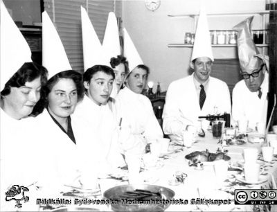 Patologiska institutionen på Paradisgatan i Lund före 1962. Luciafest.
Ur CG Ahlströms album Institutionen för Patologi, Paradisgatan, Dess chef och personal 1944 - 1962. Luciafest i slutet på 1950-talet. Vid bordets kortände från vänster prosektor Nils O. Berg och docent Nils Stormby.
Nyckelord: Lasarettet;Lund;Universitetssjukhuset;USiL;Patologiska;Institutionen;Avdelningen;Anställda;Personal;Luciafest