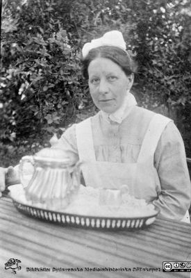 Husmor Lisa Warfvinge i lasarettsparken i Helsingborg
Från en kontorspärm på Medicinhistoriska Museet i Helsingborg märkt "Äldre fotografier från med. + kir.klin.”. Foto troligast under 1900-talets två första decennier. Husmor Lisa Warfvinge i lasarettsparken.
Nyckelord: Lasarettet;Helsingborg;Husmor;Park