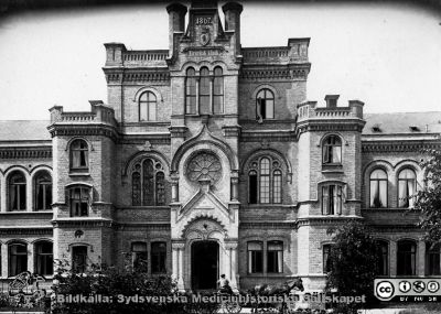 Gamla kirurgiska kliniken i Lund, från 1867-1868.
1867 års kirurgiska klinik på Lasarettet i Lund, fasad mot öster med huvudingången. Hästskjutsen talar för att bilden är tagen under något av husets tidiga decennier. Det stod klart 1867. Växtligheten pekar på att huset är fotograferat åtminstone några år senare. Byggnaden disponeras nu av Lunds universitet och används som studentcentrum. Bildkälla Denise Andersson 2021. Ur  hennes mans farfars efterlämnade bilder. Denne var Charly Urbanus Andersson, 18920525-3918, född i Ljunits, Sjörups församling vid Ystad, död 1974-02-14 och då kyrkobokförd på S Vallösa 5, 27012 Rydsgård. Han var  skräddare och fotograf, bosatt i Vallösa utanför Ystad.
Nyckelord: Lasarettet i Lund;Kirurgisk klinik.Gamla kirurgen