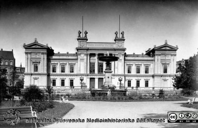 Lunds universitets huvudbyggnad vid Universitetsplatsen
Lunds universitets huvudbyggnad vid Universitetsplatsen. Fasad mot öster. Skulpturerna på taket (sfinxerna) var nertagna under några decennier i mitten på 1900-talet. De var gjorda i betong som vittrade sönder och de blev farliga att ha kvar. Vid entrédörrarna stod ursprungligen fyra stora kvinnostatyer (”fakultetsmadamerna"), men de togs bort någon gång i mitten av 1900-talet av samma skäl. Bilden är kanske tagen någon gång i mitten av 1900-talet, för fakultetsmadamerna är borta. Bildkälla Denise Andersson 2021. Ur  hennes mans farfars efterlämnade bilder. Denne var Charly Urbanus Andersson, 18920525-3918, född i Ljunits, Sjörups församling vid Ystad, död 1974-02-14 och då kyrkobokförd på S Vallösa 5, 27012 Rydsgård. Han var  skräddare och fotograf, bosatt i Vallösa utanför Ystad.
Nyckelord: Lunds universitet;Huvudbyggnad.;Fasad;Universitetsplatsen